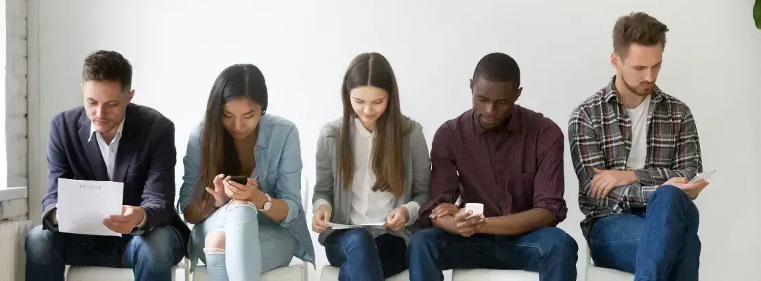 5 millennials who need life insurance are sitting down next to each other looking at computers and phones